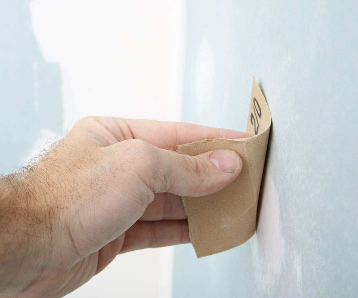 Someone removing paint from wall