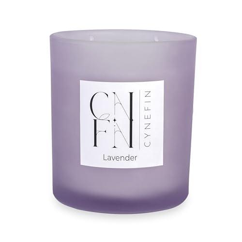 A purple glass candle jar with a lit two wick candle inside.