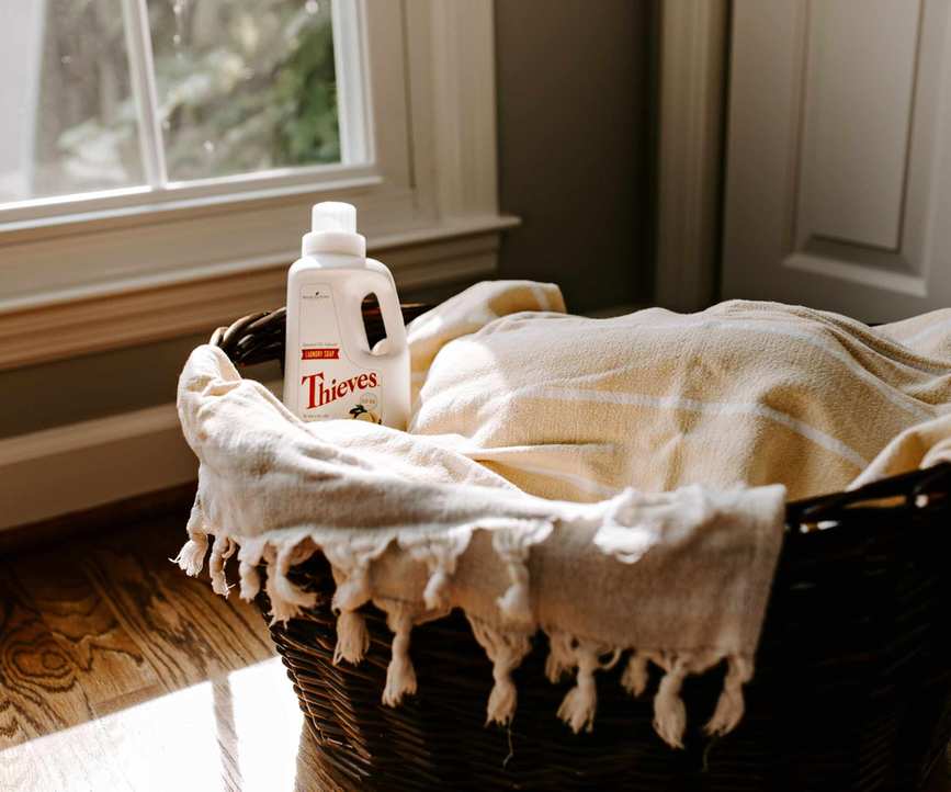A wicker laundry basket filled with clothes and detergent