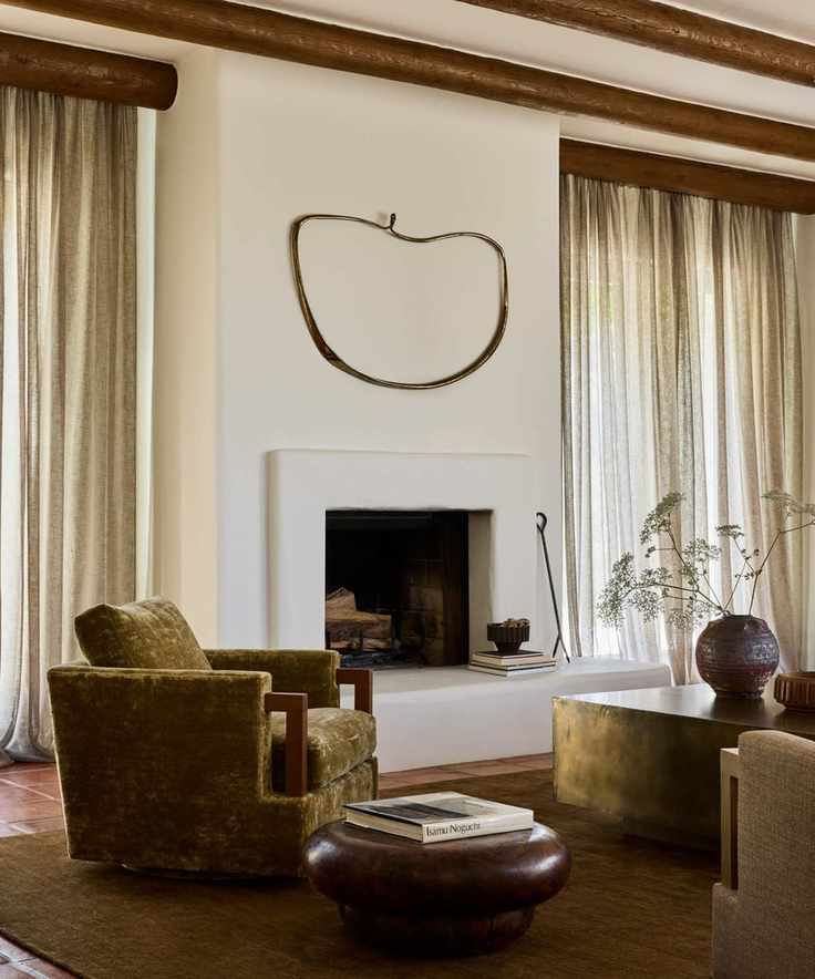 An adobe home living room showcasing white plastered walls, an earthy green armchair, and a round wooden table