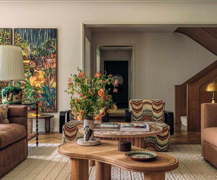 Modern living room with statement artwork curved wooden coffee table and brown sofas