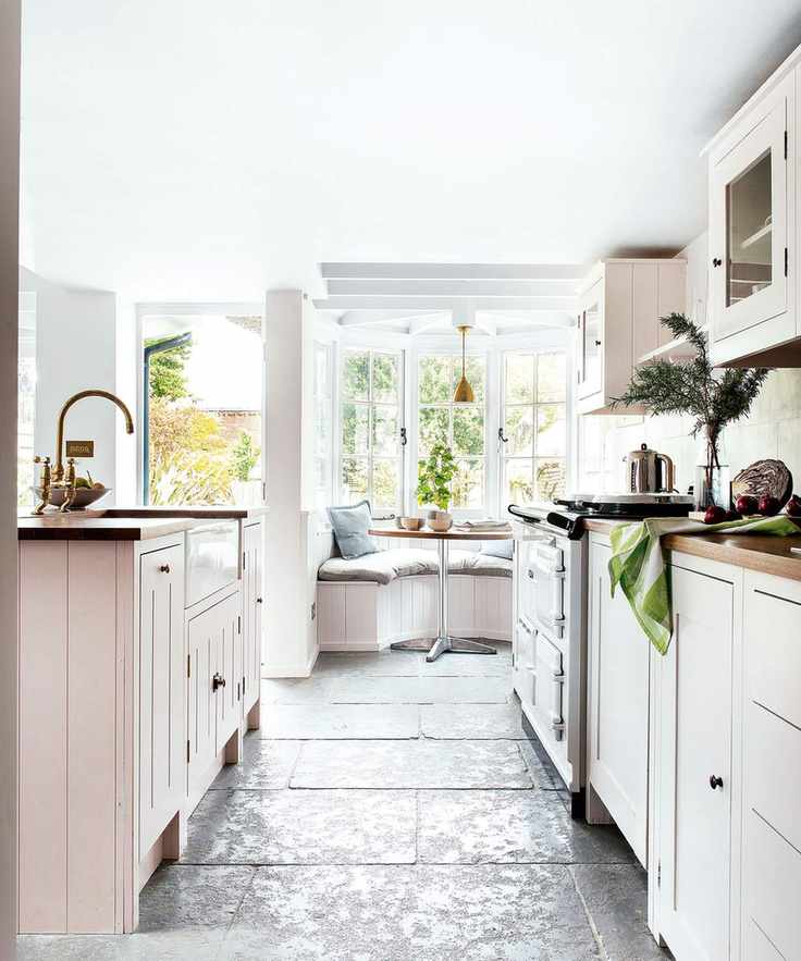 White country kitchen, View between kitchen island and units towards bay window and open front door.