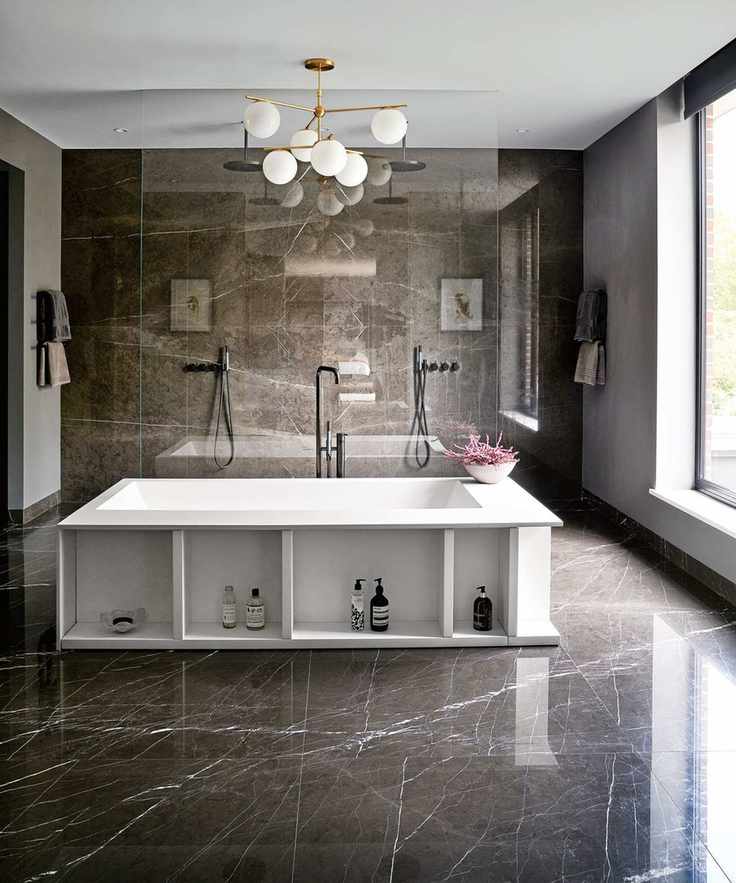 Bathroom with gray marbled floor and walls and large central white bath