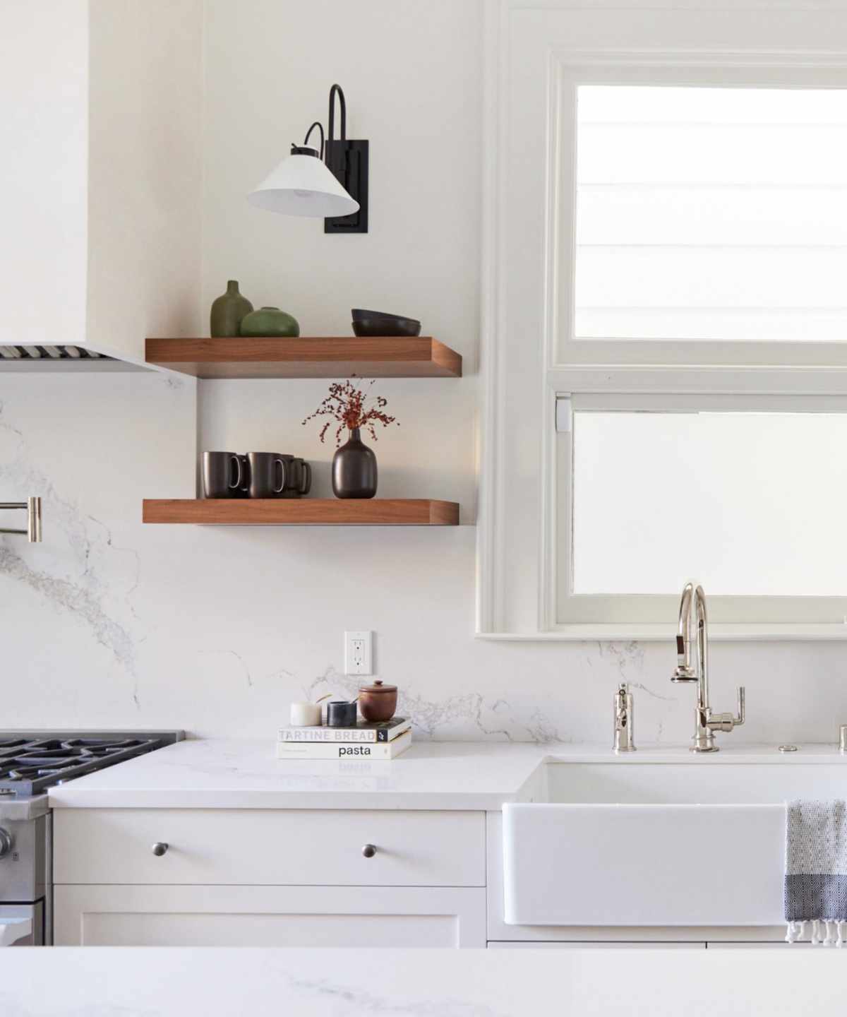 white kitchen with marble countertops, dark wood open shelving, nickel fixtures and fittings