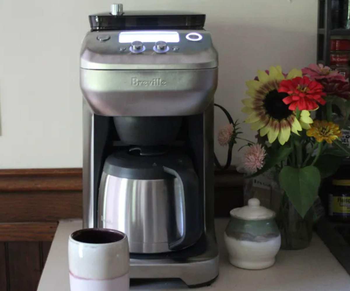 Breville Grind Control Coffee Maker on a countertop with a coffee mug and flowers