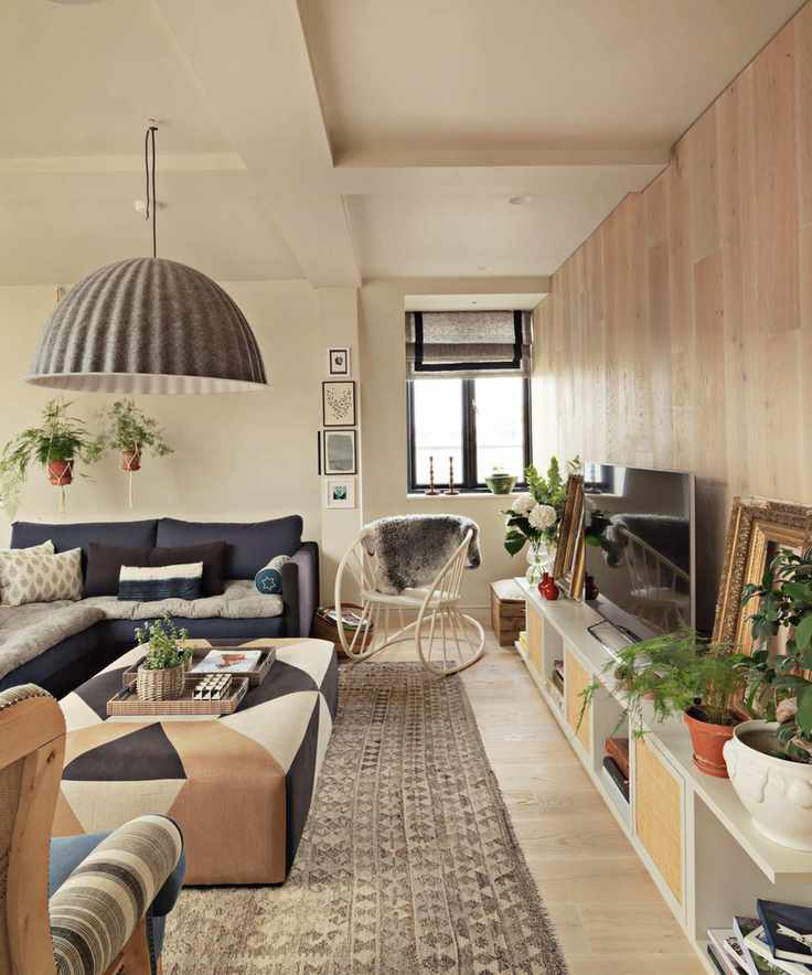 View of living area with wooden floor, large rug, low media unit featuring television and accessories