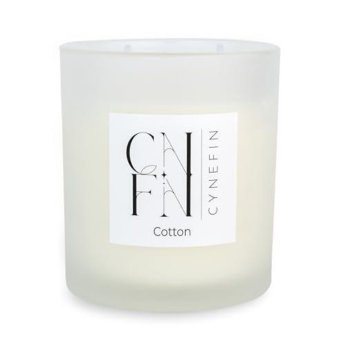 A white glass candle jar with a lit two wick candle inside.