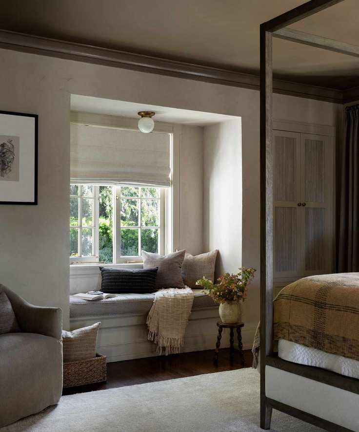 Cozy bedroom with built-in window seat for reading and a vintage four-poster bed