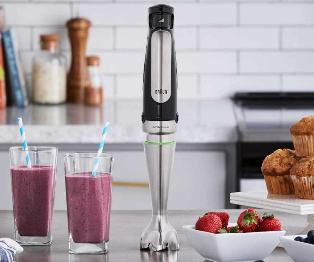 Braun immersion hand blender on a countertop next to smoothies and muffins