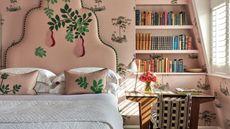 pink bedroom with floral wallpaper and a pink embroidered floral headboard with white bed linens, green bed skirt and upholstered ottoman
