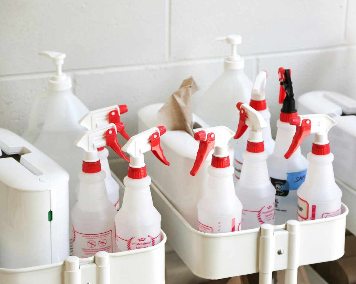 white empty spray bottles with red lids sat in white baskets, ready to fill with cleaning solutions