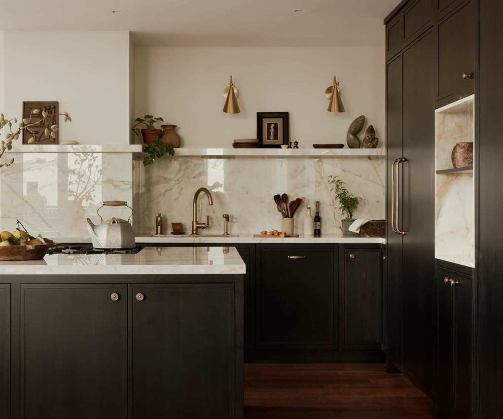 A dark blue kitchen with white walls and marble across the counters, walls, and shelves