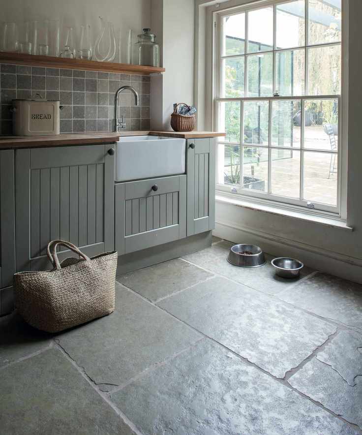 A dark mudroom with two dog bowls, a sink area and a large window