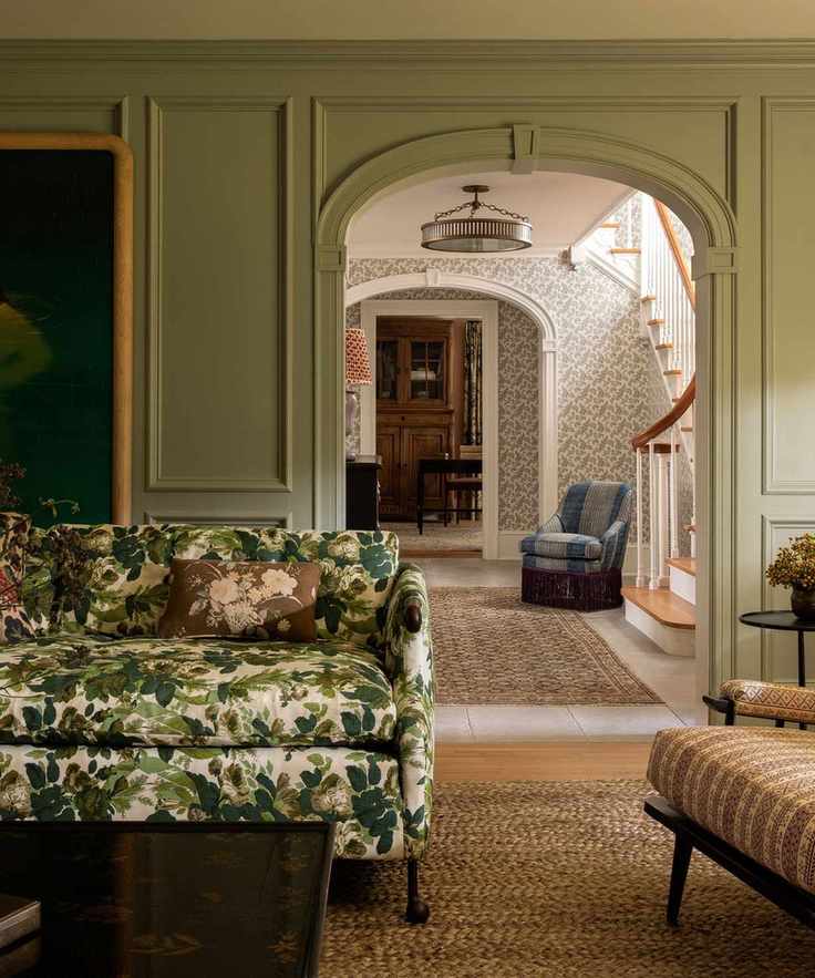 A green living room designed by Heidi Caillier with a patterned couch and arched doorway