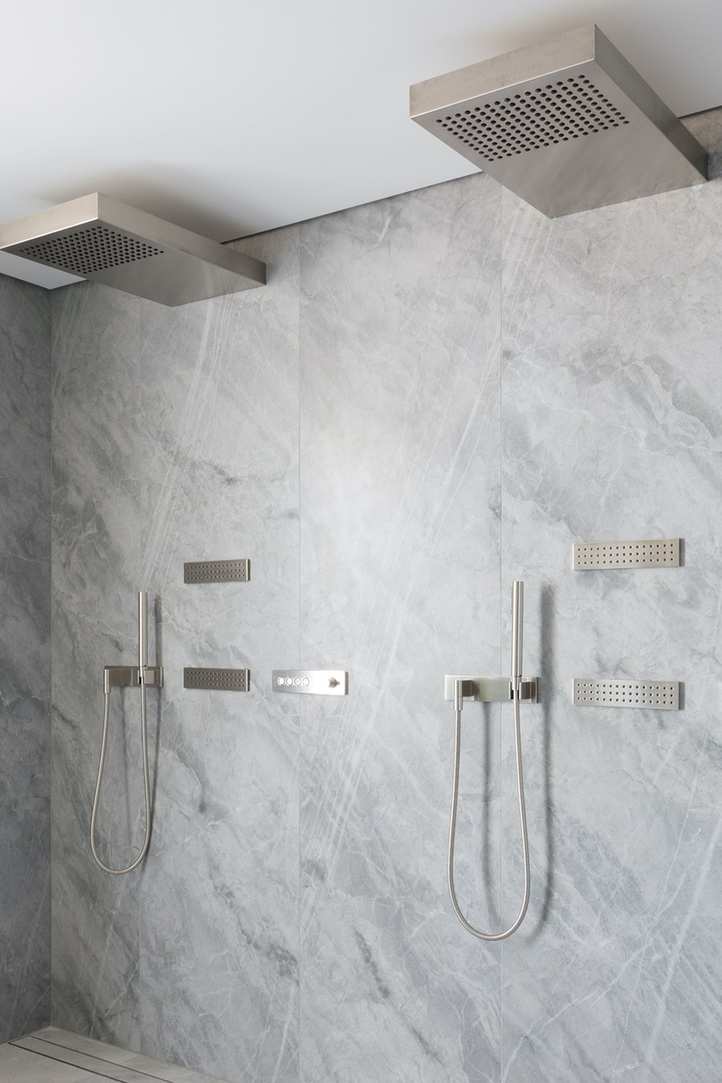 Shower design for a compact bathroom illustrated by sleek chrome fittings in a marble setting.