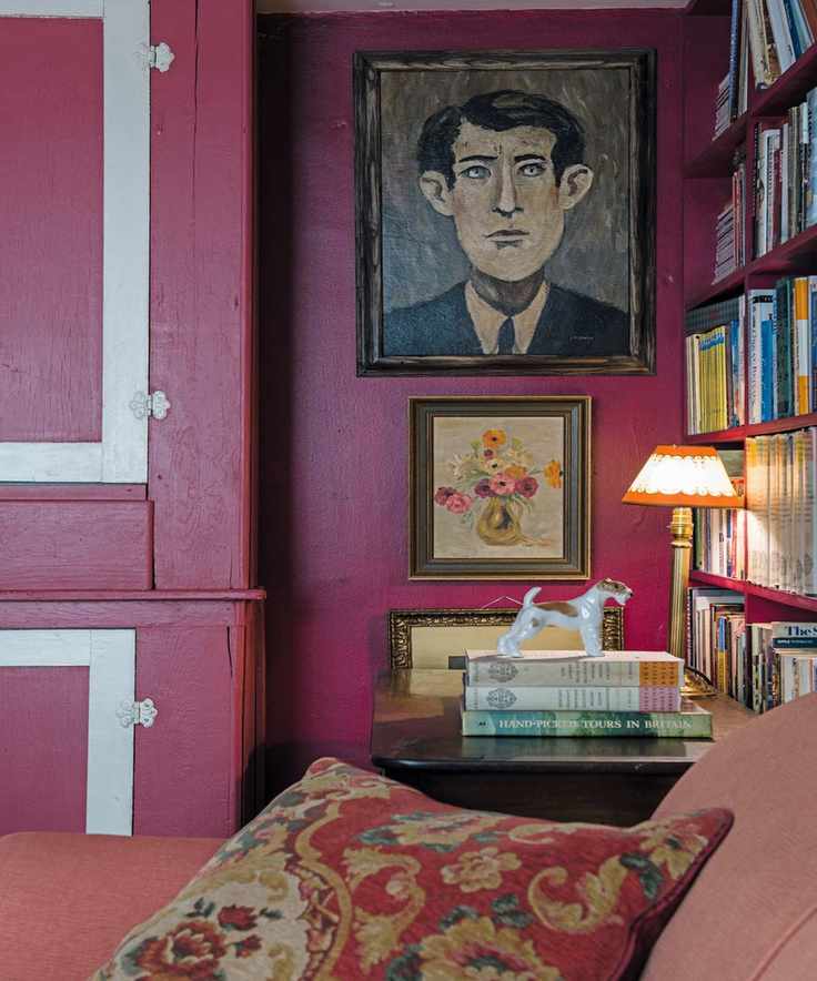 Bright pink living room with painted walls and cushions, featuring books and artwork on display