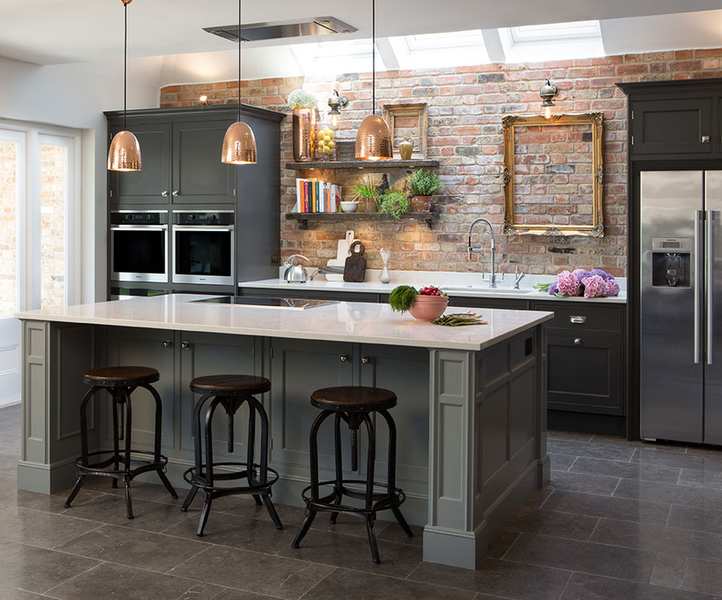 A kitchen with a large green island and exposed brick wall