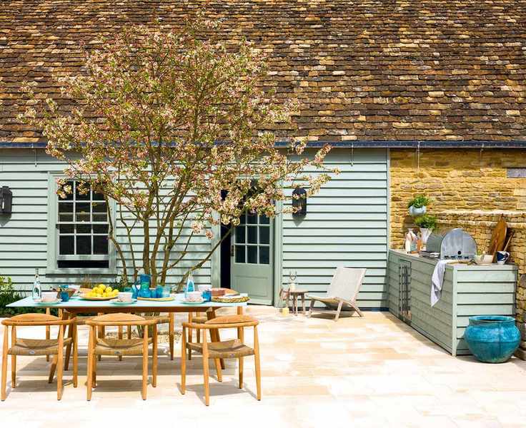 A wooden table laid with lunch in front of a green wooden clad house