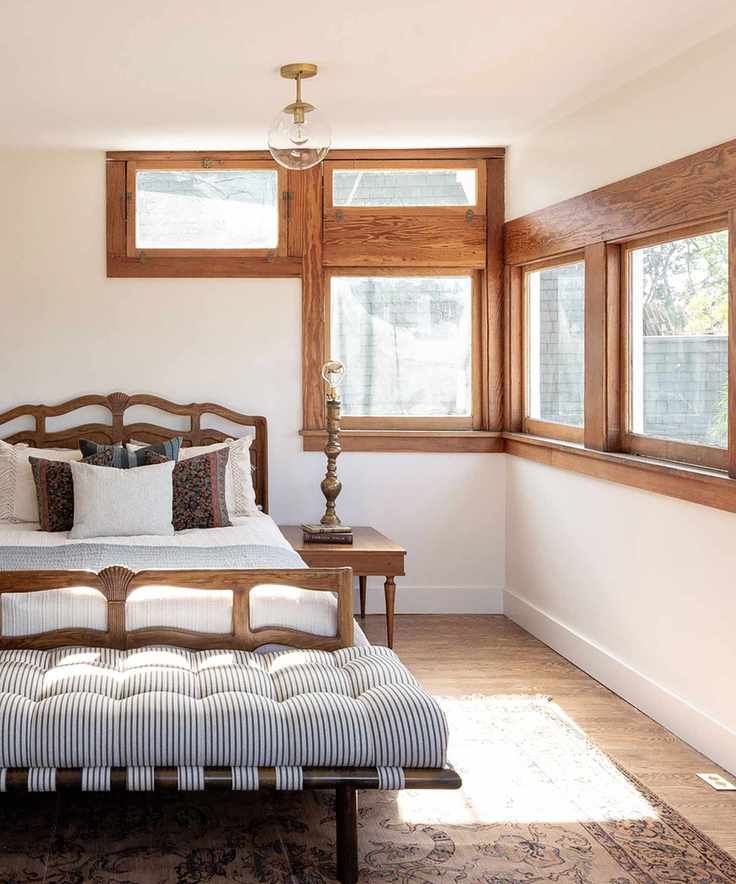 Bedroom with unique square windows, a double bed, and a striped daybed at the foot