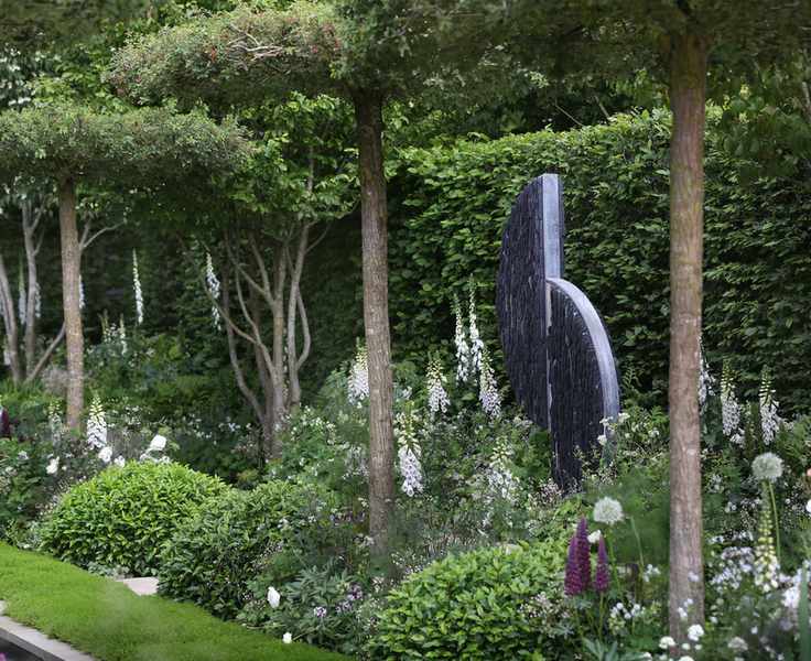 evergreen domes and standard trees mixed with looser planting in simple palette and statue