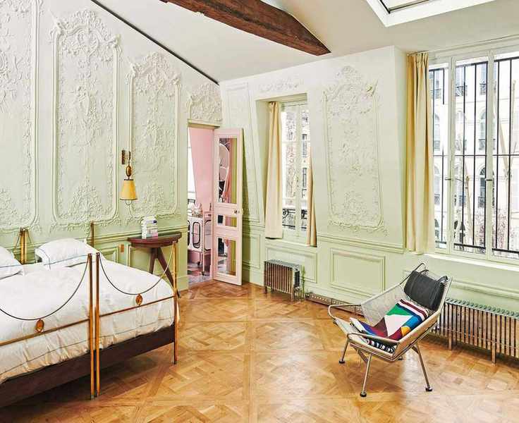 a pale green ornate bedroom in a parisian apartment with vintage italian furniture