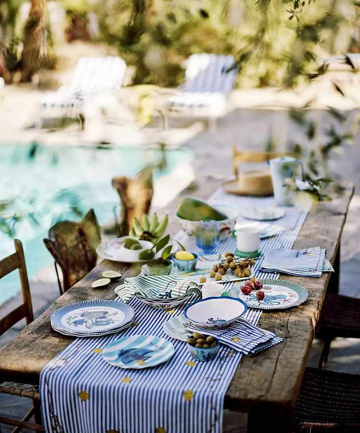Mediterranean style rustic wooden tablescape next to a pool with striped pool loungers
