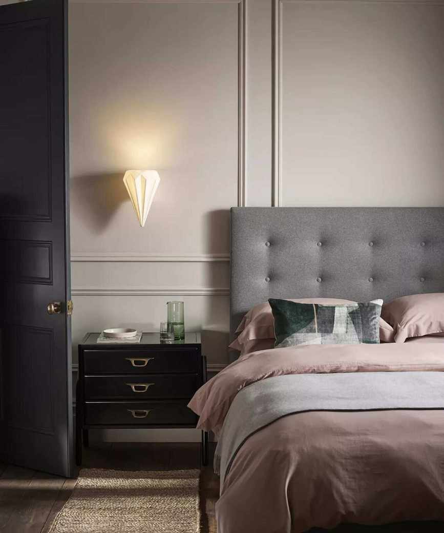 A padded headboard against a white, traditionally pannelled wall