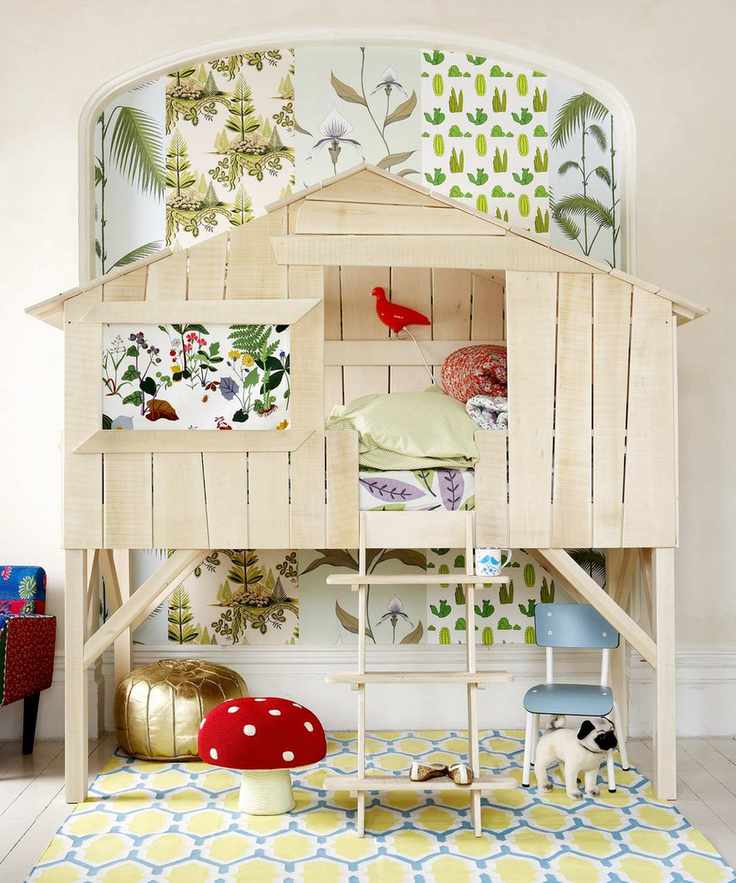 A children's bedroom featuring a loft bed designed like a treehouse with plant-themed wallpaper