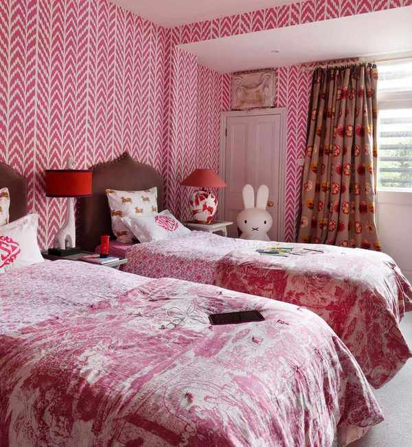 Pink bedroom for kids with zig-zag pink and white patterned wallpaper and twin beds.