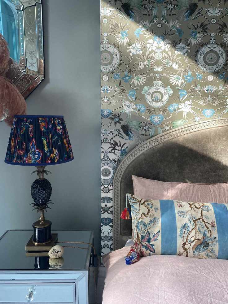 Bedroom with wallpaper above bed, gray painted alcove and nightstand with lamp