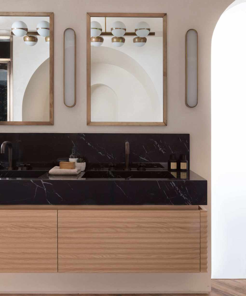 Midcentury bathroom featuring black marble counter and dual sinks