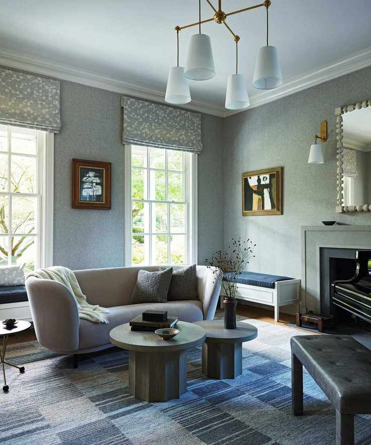 a soft blue music room with patchwork rug, fireplace, curved couch and round coffee tables