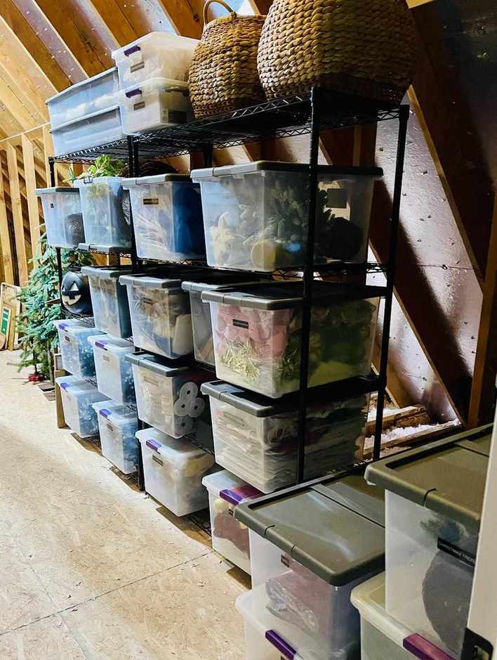 Black attic shelving with clear plastic totes on it.