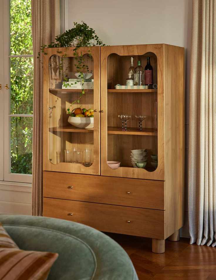 Wooden curio cabinet showcasing a diverse collection of glassware and ceramics