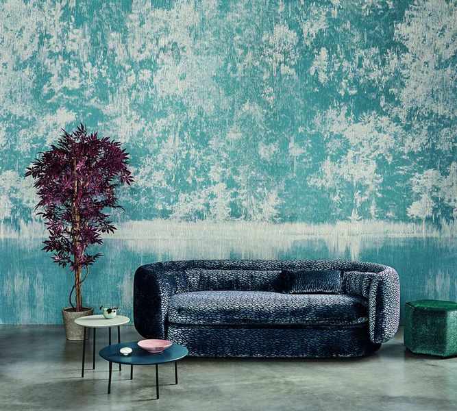 blue wall mural in living room with blue velvet textured sofa, coffee tables, concrete floor