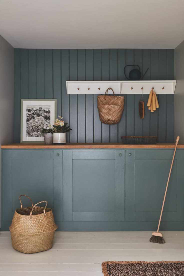 blue and green painted laundry room with white shelf pegs wooden worktop