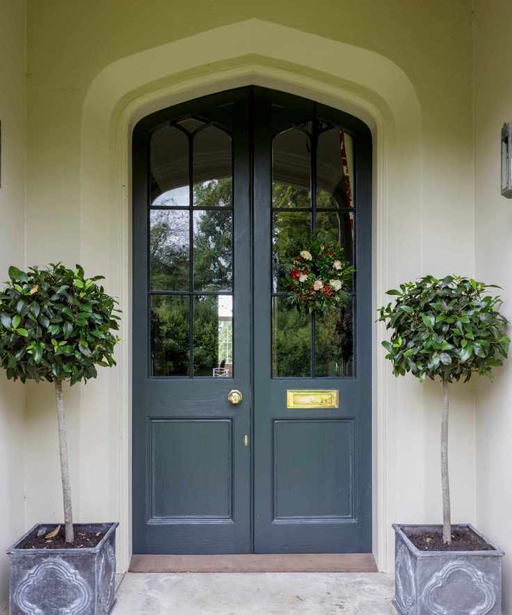 a front door with two split doors painted in blue and two small potted trees