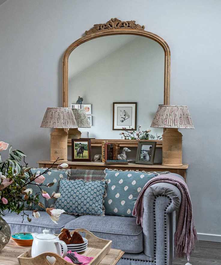 Small living room lighting ideas featuring two small fabric table lamps in front of a large gilded mirror.