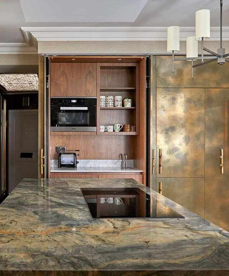 an art deco inspired deep gold and walnut kitchen with a statement light and dark wood coffee station