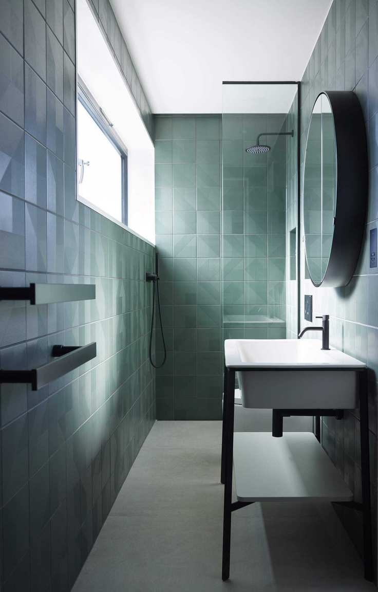 A green-tiled bathroom with a vanity in front
