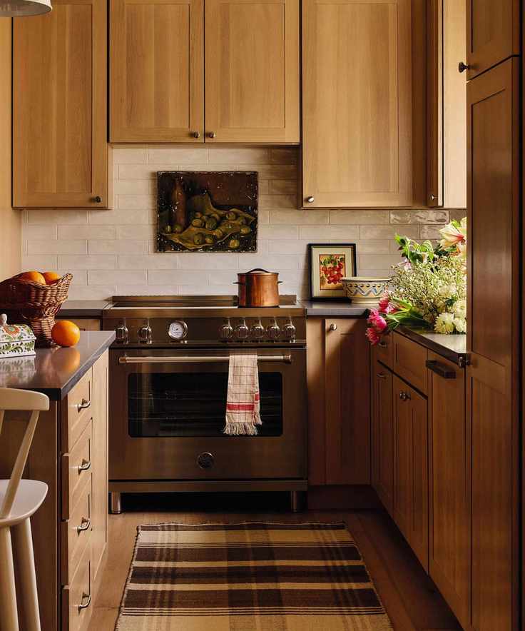 a small wooden kitchen in the Catskills with a stainless steel rangecooker, vintage decor and a plaid runner rug