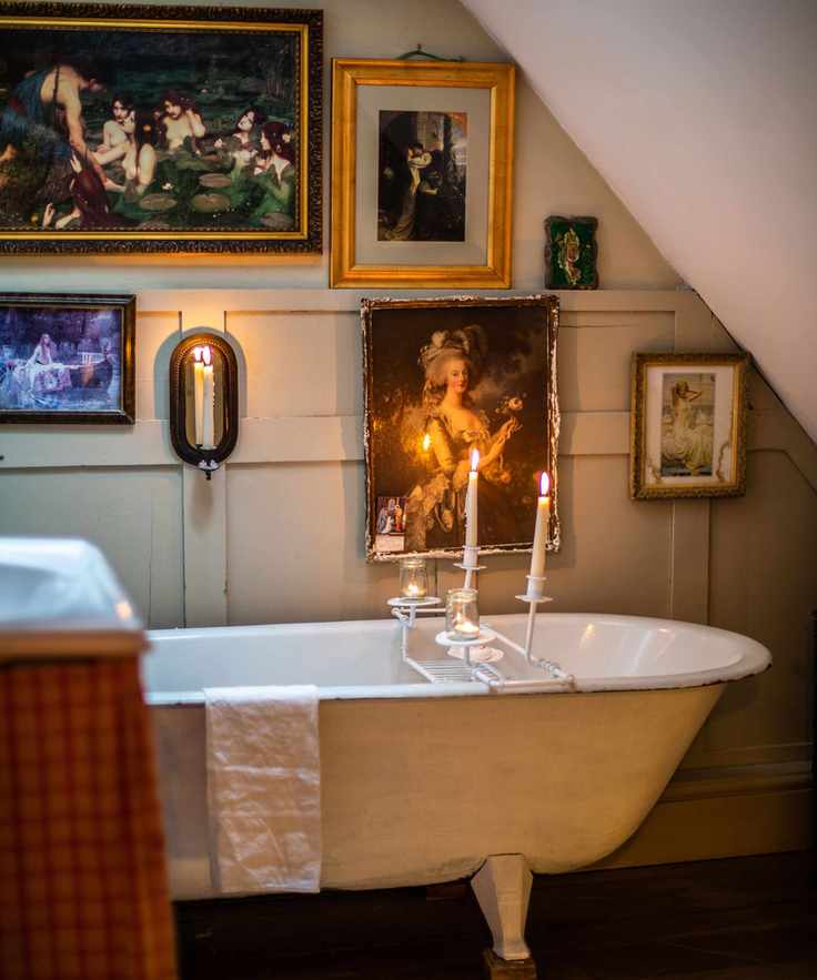 vintage bathroom with freestanding reclaimed bath and old paintings on wall