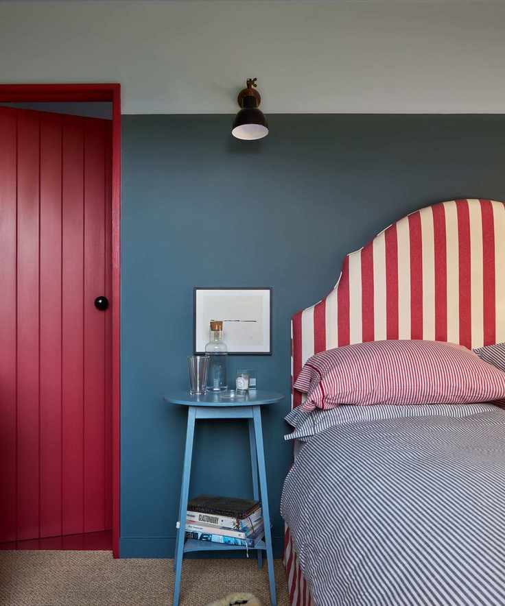 bedroom with blue walls, red and white striped headboard, blue nightstand and red door