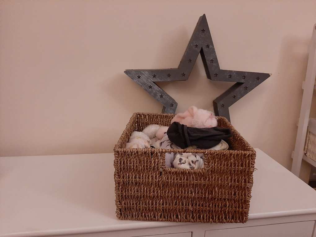 a light brown woven basket filled with assorted socks sat on top of a white wooden set of drawers