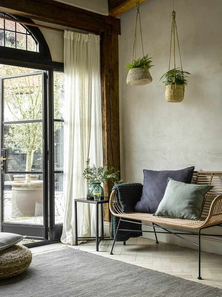 A foyer with large windows, wicker hanging baskets and wicker furniture