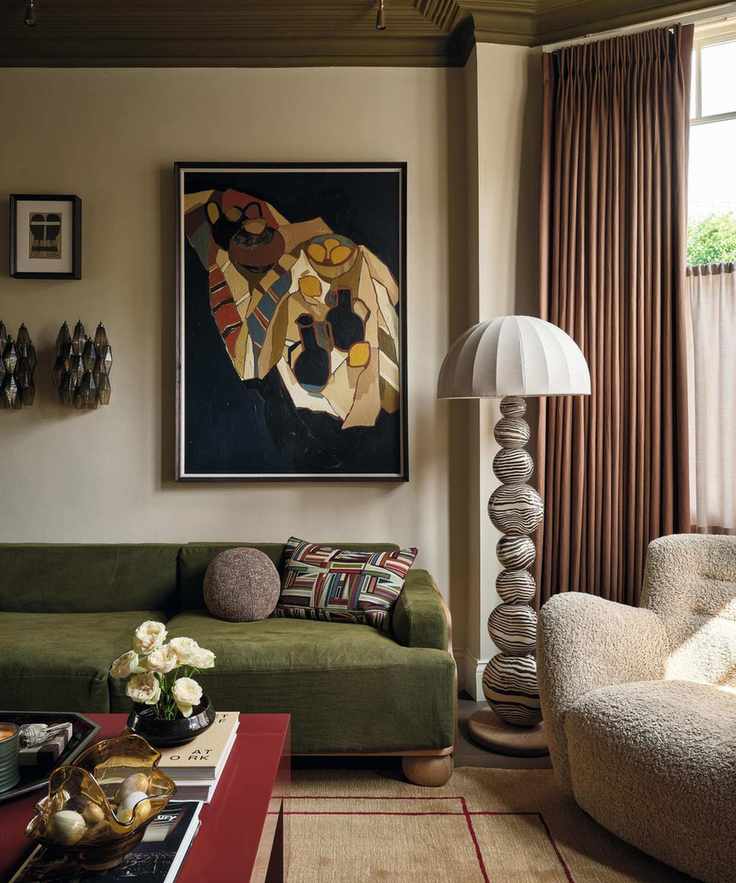 a traditional Victorian london home designed with statement artwork, a green sofa, sheepskin armchairs in the bay window and a ceramic floor lamp