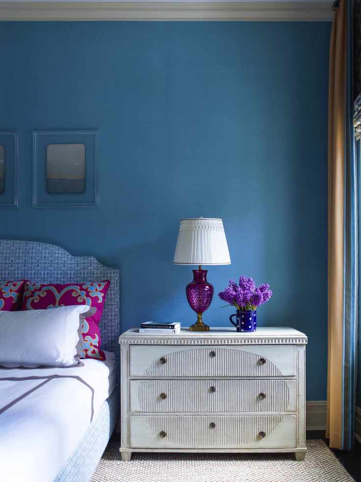 Blue wall and picture frames, blue and white patterned headboard
