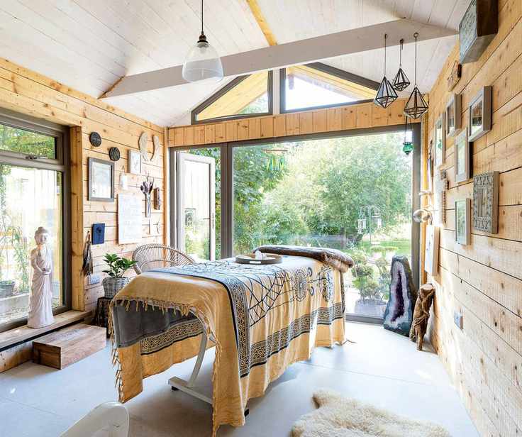 treatment room with treatment couch and wooden walls with neutral colors and big picture window to garden