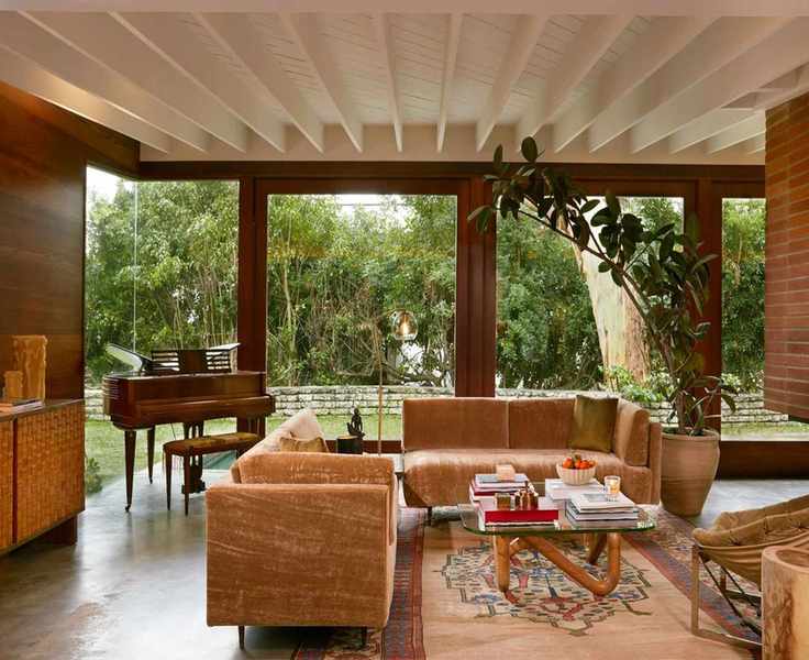 a mid-century living room with two mohair couches, a glass coffee table, wood panelled walls, and a white ceiling