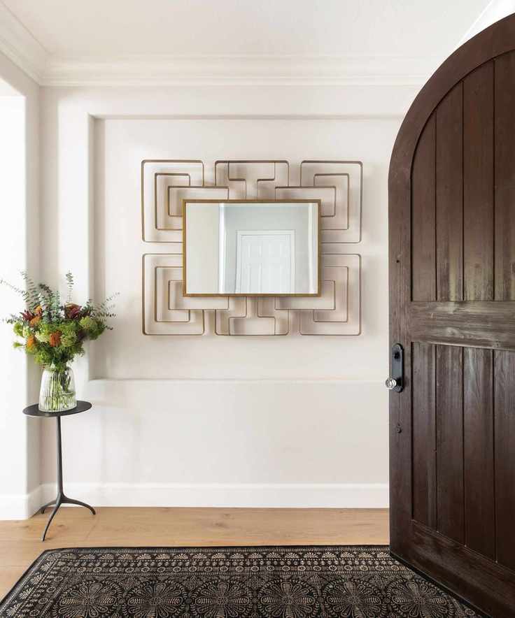 arched wooden front door with white walls and vintage rug in hallway